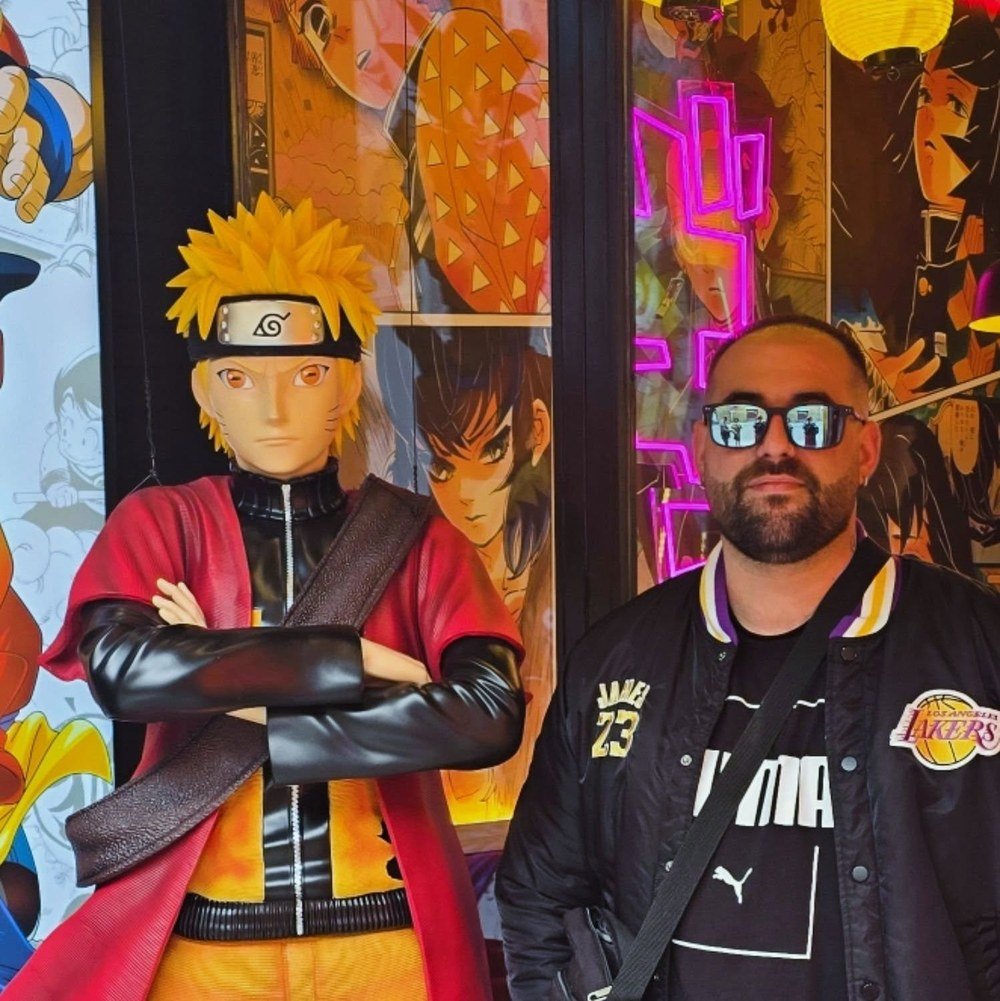 El creador de GameFusion Studios junto a una figura de Naruto, rodeado de ilustraciones de anime.
